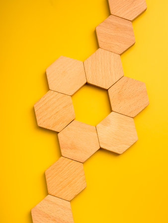 Empty wooden hexagon blocks connected on yellow background. Teamwork, organization structure, and...