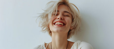 Joyful woman with short bleached hair in light clothes on a white background color photoの素材