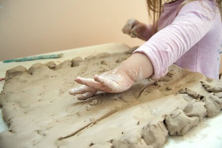 little girl works with clay at the table. Time for childrens creativity. Clay petal with a baby. Previously, the development of the child. A Conscious Childhoodの写真素材