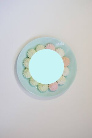 Sweet paste colored bise on a delicate blue plate on a white table. Good morning. Flat layの写真素材