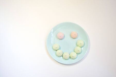 Sweet paste colored bise on a delicate blue plate on a white table. Good morning. Flat layの写真素材
