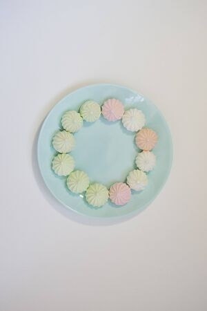 Sweet paste colored bise on a delicate blue plate on a white table. Good morning. Flat layの写真素材