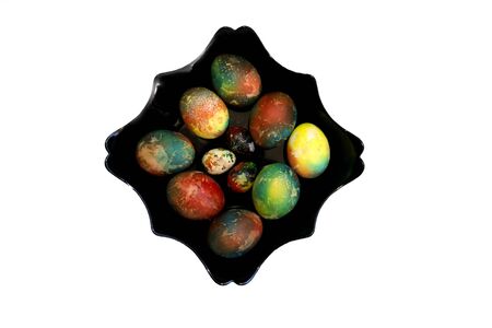 A group of brightly colored Easter eggs on a black curly plate on a white background. A place for text. Easter. Creative abstract painting of eggs.の写真素材