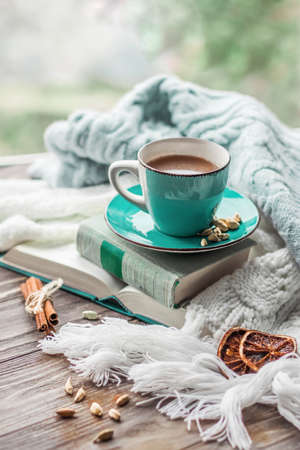 Morning coffee. Cozy composition: a cup of coffee on a wooden table and a warm sweater, open books. Still life concept. Copy space.の写真素材