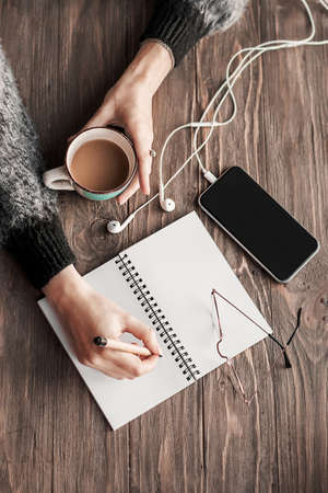 Coffee break in a cafe for inspiration.Work from home. Blank notebook, a cup of coffee in a female...