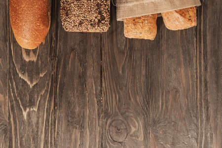 Fresh loaves of assorted bread on an old wooden background with copy space. Food background.の写真素材