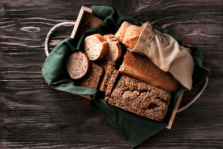 Fresh loaves of bread on a wooden tray and brown wooden background.
