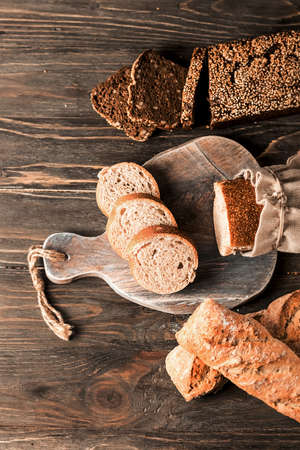 Fresh loaves of assorted bread on an old wooden background. Food background.の写真素材