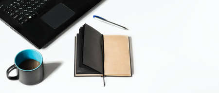 Modern white office desk with laptop, cup of coffee and notebook for notes. Top view with copy space, flat tanning bed.の写真素材