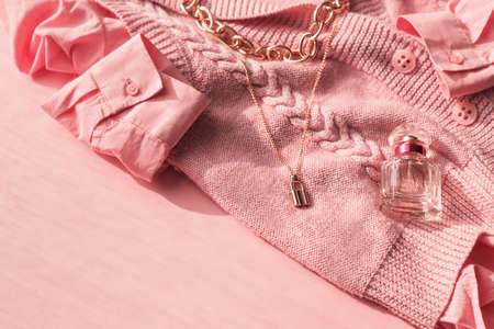 Background with fashionable clothes. Pink jersey, shirt, stylish feminine accessories and a bottle of perfume on a pink background with copy space. Beauty blog concept.の写真素材