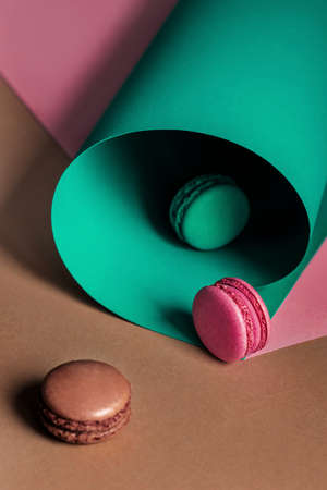 French macaroons on a multi-colored paper background with place for text. Pastry chef app with copy space. Creative conceptの写真素材