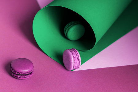 French macaroons on a multi-colored paper background with place for text. Pastry chef app with copy space. Creative conceptの写真素材