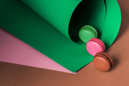 French macaroons on a multi-colored paper background with place for text. Pastry chef app with copy space. Creative conceptの写真素材
