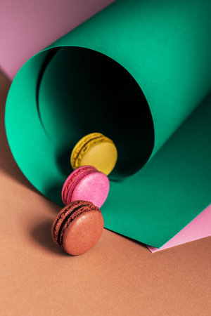 French macaroons on a multi-colored paper background with place for text. Pastry chef app with copy space. Creative conceptの写真素材