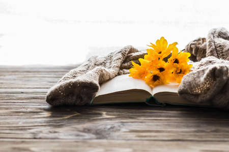 Cozy morning. Opened book and a bouquet of flowers on a wooden background with copy space. Cozy home interior, lifestyle, romantic atmosphereの写真素材