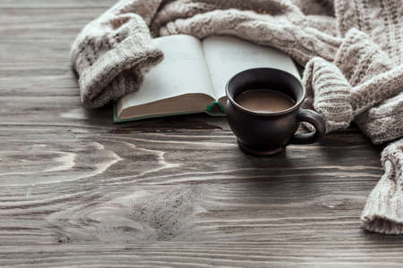Morning coffee. Cup of coffee on a wooden table and a warm sweater on a background of yellow flowers Copy space.の写真素材