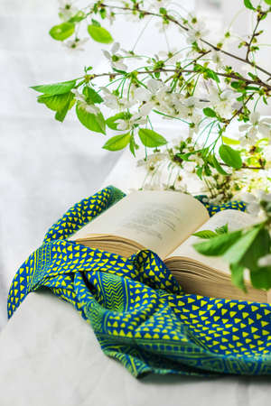 Open book and blooming spring branches on a white background. Glass vase with flowers. Good morning lifestyle, slow life concept.の写真素材