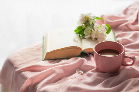 The atmosphere of a romantic morning, coffee in bed. A cup of coffee on a pink silk bed, a small...