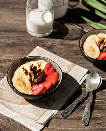 Healthy Vitamin Breakfast. Bananas, strawberries, nuts and dates in plates on a white background. Vegetarian and fitness food. Beautiful serving.の写真素材