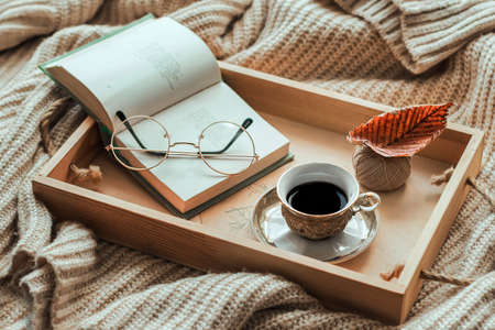 Coffee in bed, romantic morning. Open book and a cup of coffee on a wooden tray. Home cozy interior, lifestyle. Selective focusの写真素材