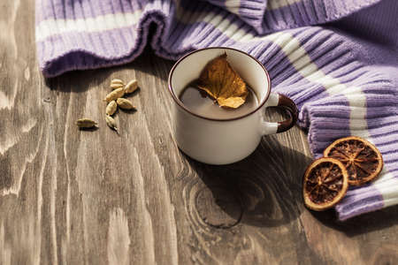 Autumn morning coffee. A cup of coffee on a wooden table and a warm sweater on a background of...