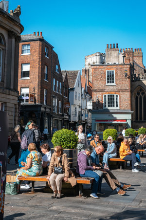 People relaxing on benches on a sunny day in the historic city center of York.