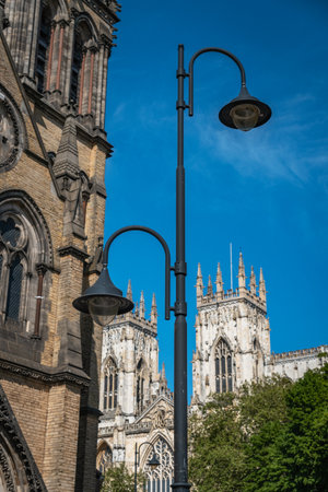 York Minster cathedral towers on a sunny summer day with a clear blue sky. High quality photoA low-angle view of the majestic Gothic architecture of York Minster, showcasing the intricate details of its stone towers against a vibrant sky.の写真素材