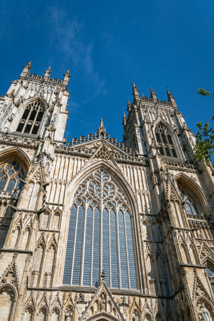 York Minster cathedral towers on a sunny summer day with a clear blue sky. High quality photoA low-angle view of the majestic Gothic architecture of York Minster, showcasing the intricate details of its stone towers against a vibrant sky.の写真素材