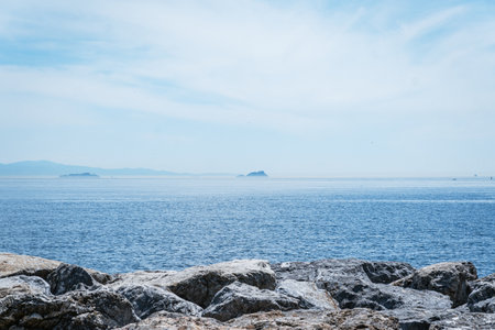A rocky shoreline with a view of the clear blue waters of the Sea of Marmara, with the Princes' Islands in the distance.の写真素材