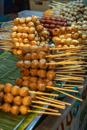Close-up of grilled Thai pork or beef meatballs on bamboo skewers, a popular street food snack.の写真素材