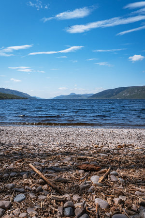A scenic horizontal view of the vast, deep blue waters of Loch Ness, Scotland, taken from the shingle and pebble beach at Dores.の写真素材