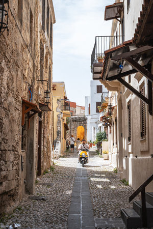 A man on a scooter in a narrow cobblestone alley in the Medieval City of Rhodesの写真素材