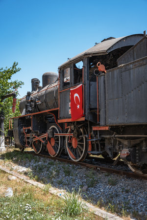 A classic black steam locomotive with vibrant red wheels and a Turkish flag is proudly displayed on...
