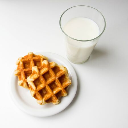 glass of milk and cookies on white backgroundの写真素材