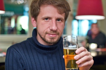 Portrait of smiling man with glass of beer in restaurantの写真素材