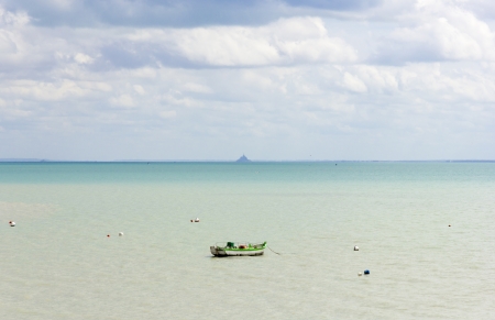 Single boat on the calm blue sea in the background of Mont Saint-Michelの写真素材