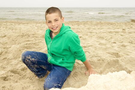 cute boy playing in sand on beach, Northern Sea coastの写真素材