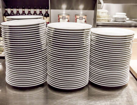 Stacks of white plates against a restaurant backgroundの写真素材
