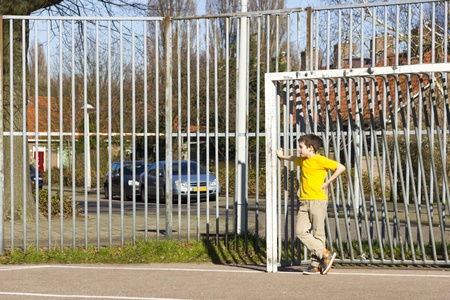 Cute boy staying in gate on the playgroundの写真素材
