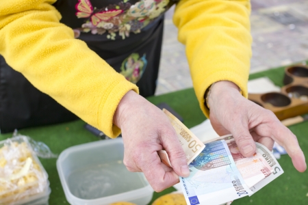 Woman seller returns change in euro in the marketの写真素材