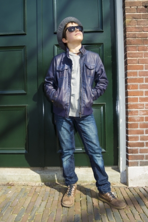 Cute teenage boy in hat (full-length portrait) on the dutch streetの写真素材