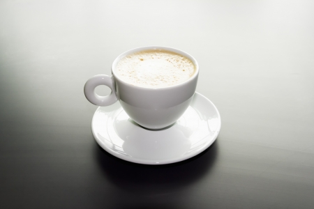 white cup of cappuccino on a black matte surfaceの写真素材