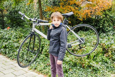 young boy carrying his bikeの写真素材
