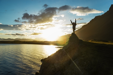 Silhouette boy staying on hill over the sun, Icelandの写真素材