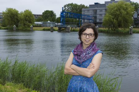 Portrait of young woman in blue dress against a dutch canalの写真素材