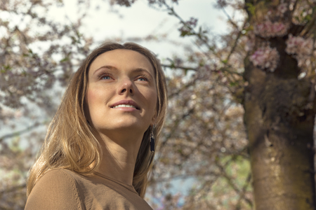 Girl with Cherry Blossom. Beautiful Blonde Young Woman with Sakura. Spring Flowers. Portraitの写真素材