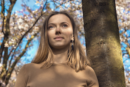 Beautiful happy young woman enjoying smell in a flowering spring garden