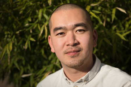 Portrait of smiling chinese young man against bamboo backgroundの写真素材