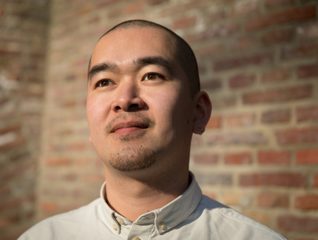 Portrait of chinese young man against red bricks wall backgroundの写真素材