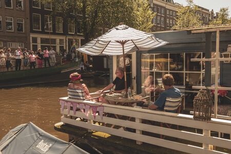 Amsterdam, Netherlands - August 3, 2013: A vintage color tone picture  of Amsterdam gay parade in a canal on a sunny day with people greeting prideのeditorial素材